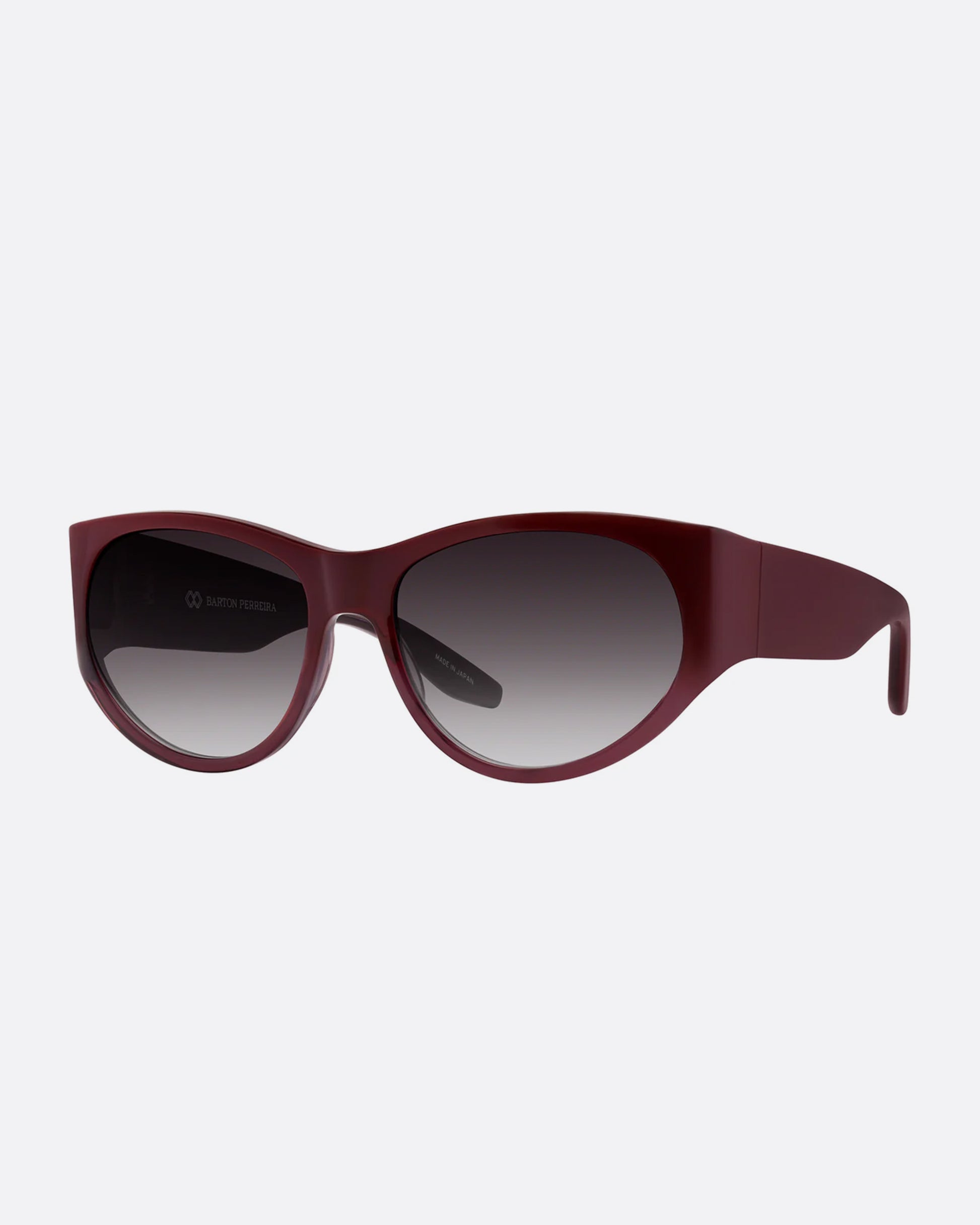 A pair of burgundy sunglasses with gradient lenses. Shown from the side.
