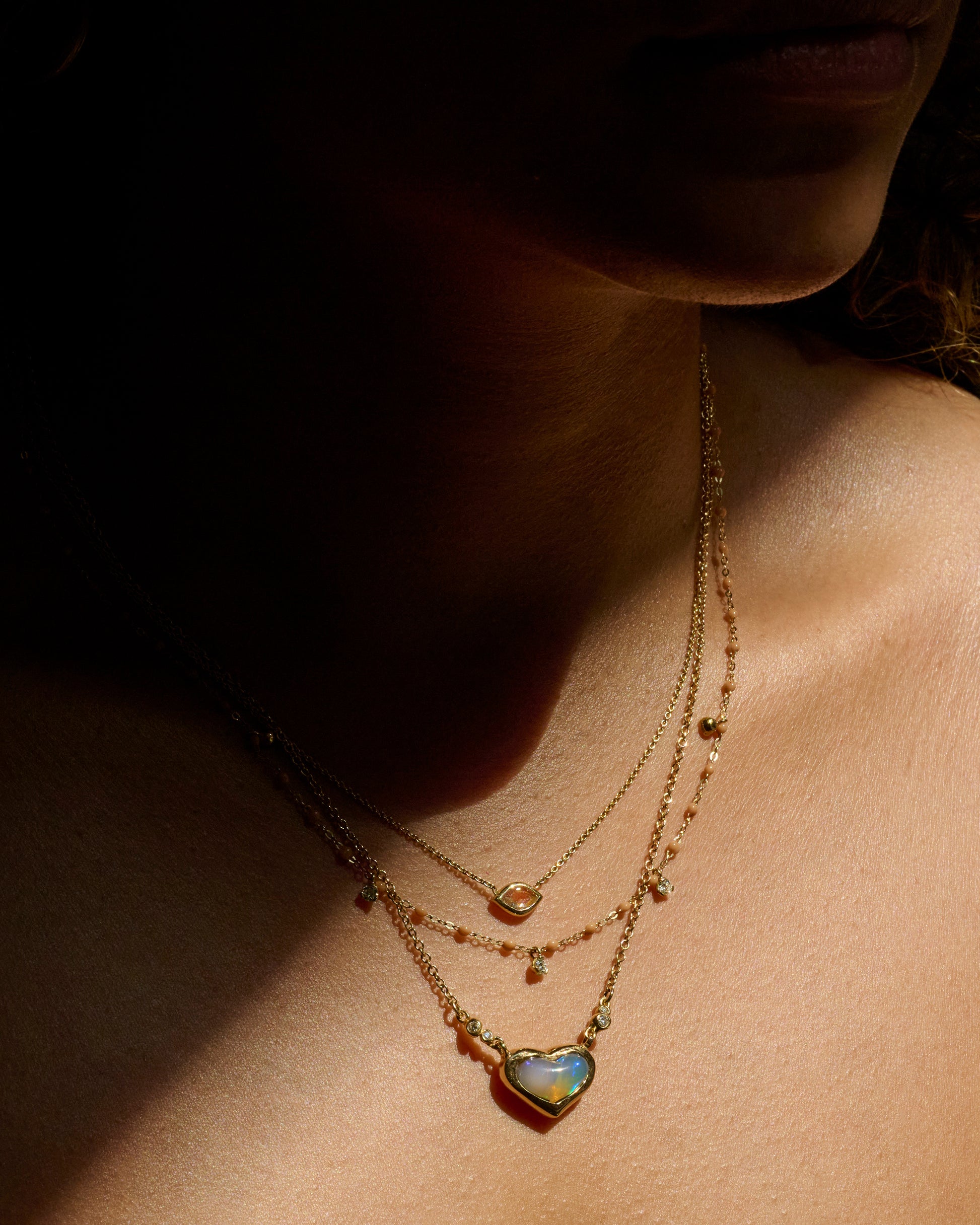 A yellow gold cable chain necklace with caramel brown resin droplets along the chain and five dangling diamond charms. Shown on a person from the front.