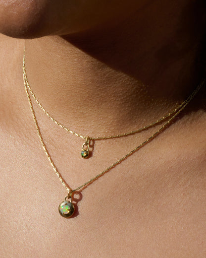 Two yellow gold necklaces, each with an opal pendant, shown from the front on a person.