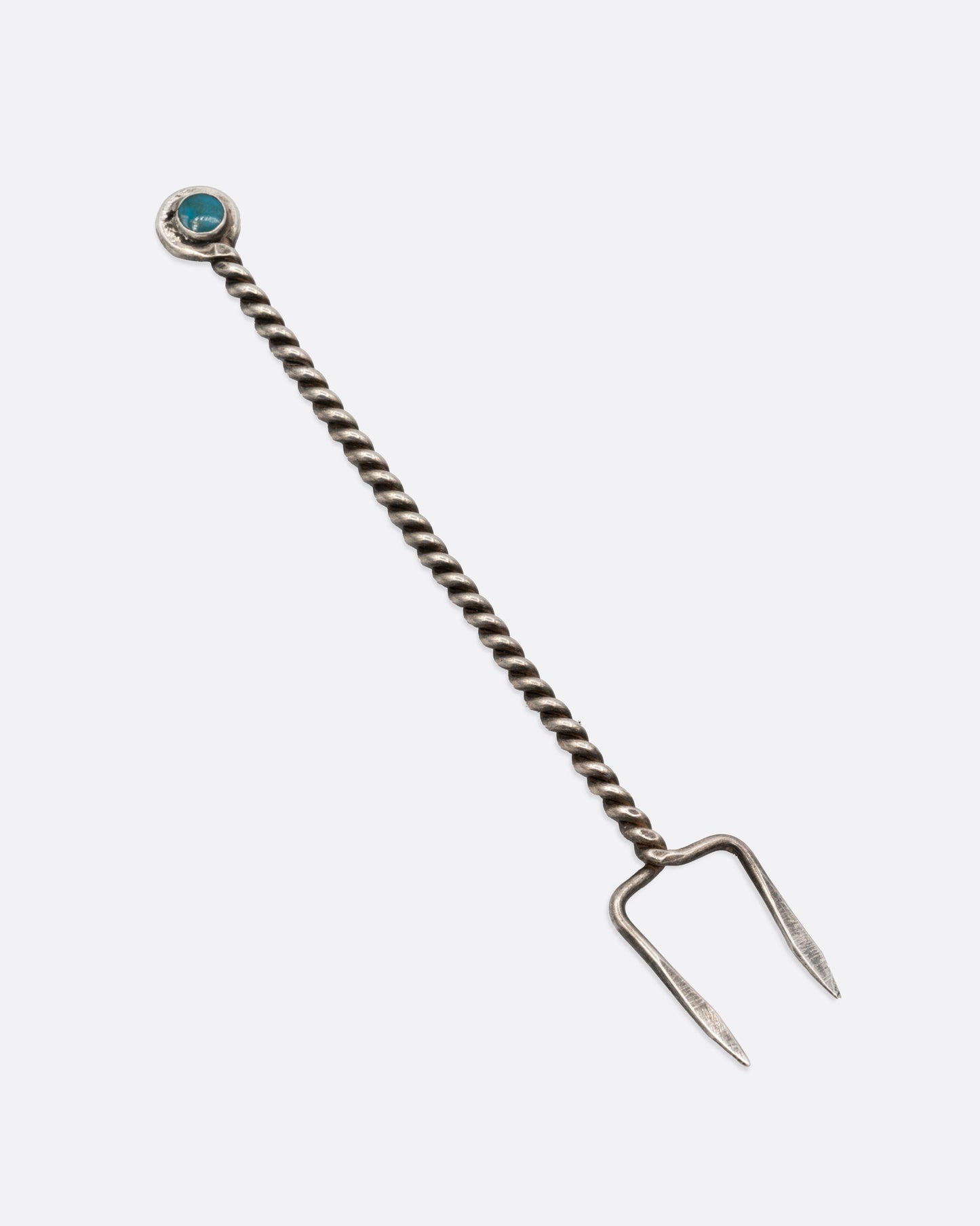A two pronged silver olive pick with a twisted handle and round turquoise stone at the bottom. Shown from the front.