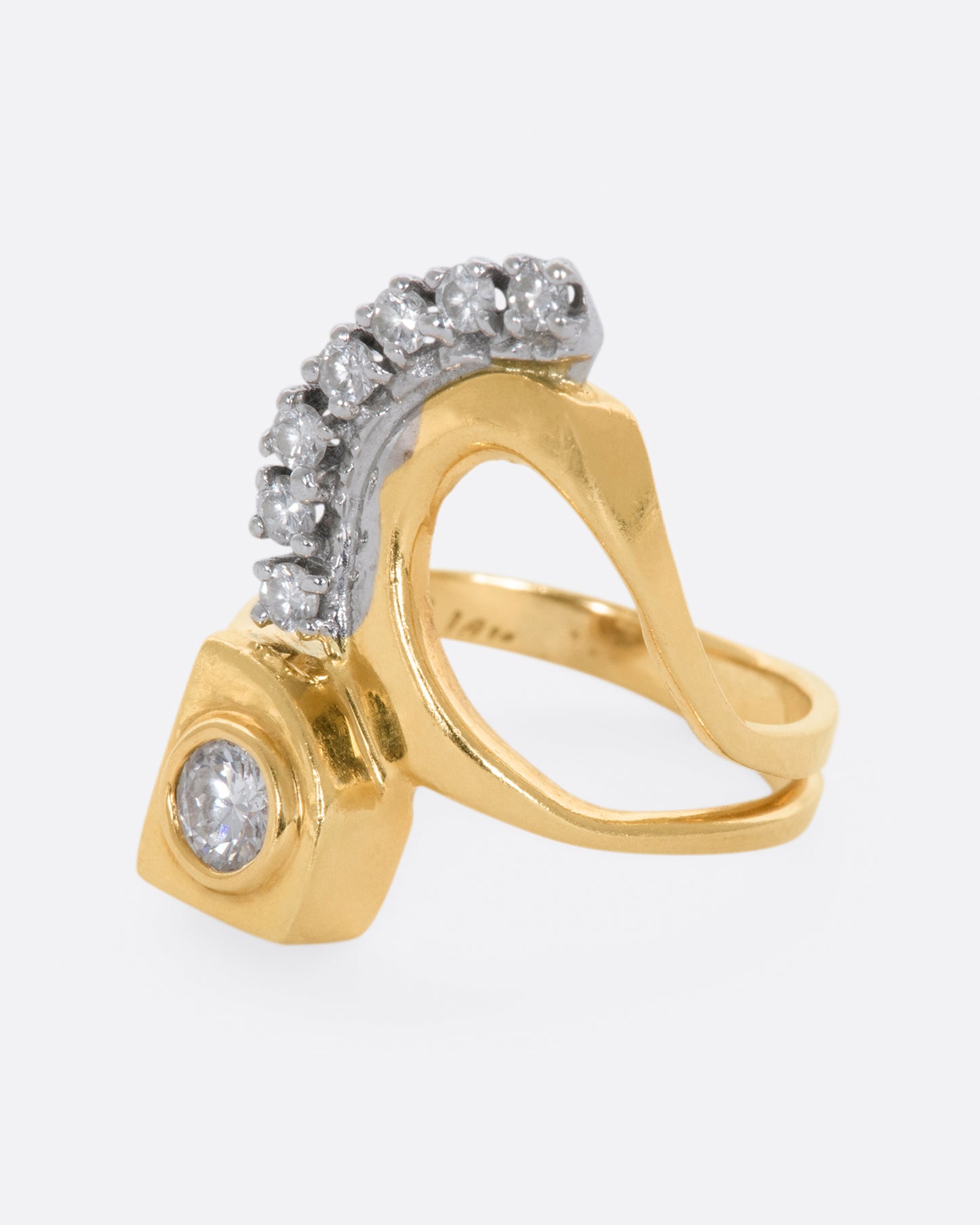 Yellow gold abstract ring with one bezel set round diamond and seven prong set diamonds. View from the left side.