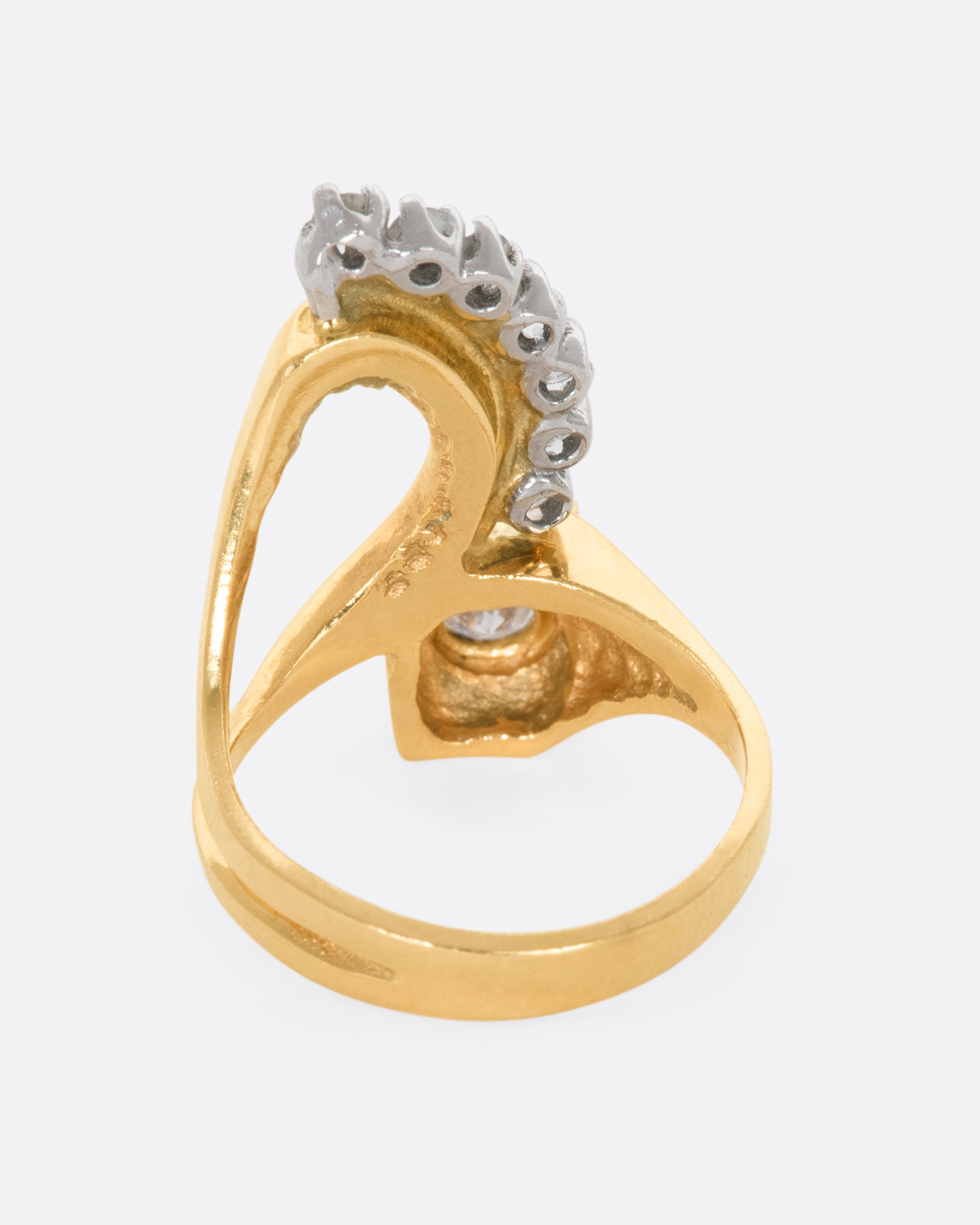 Yellow gold abstract ring with one bezel set round diamond and seven prong set diamonds. View from the back.