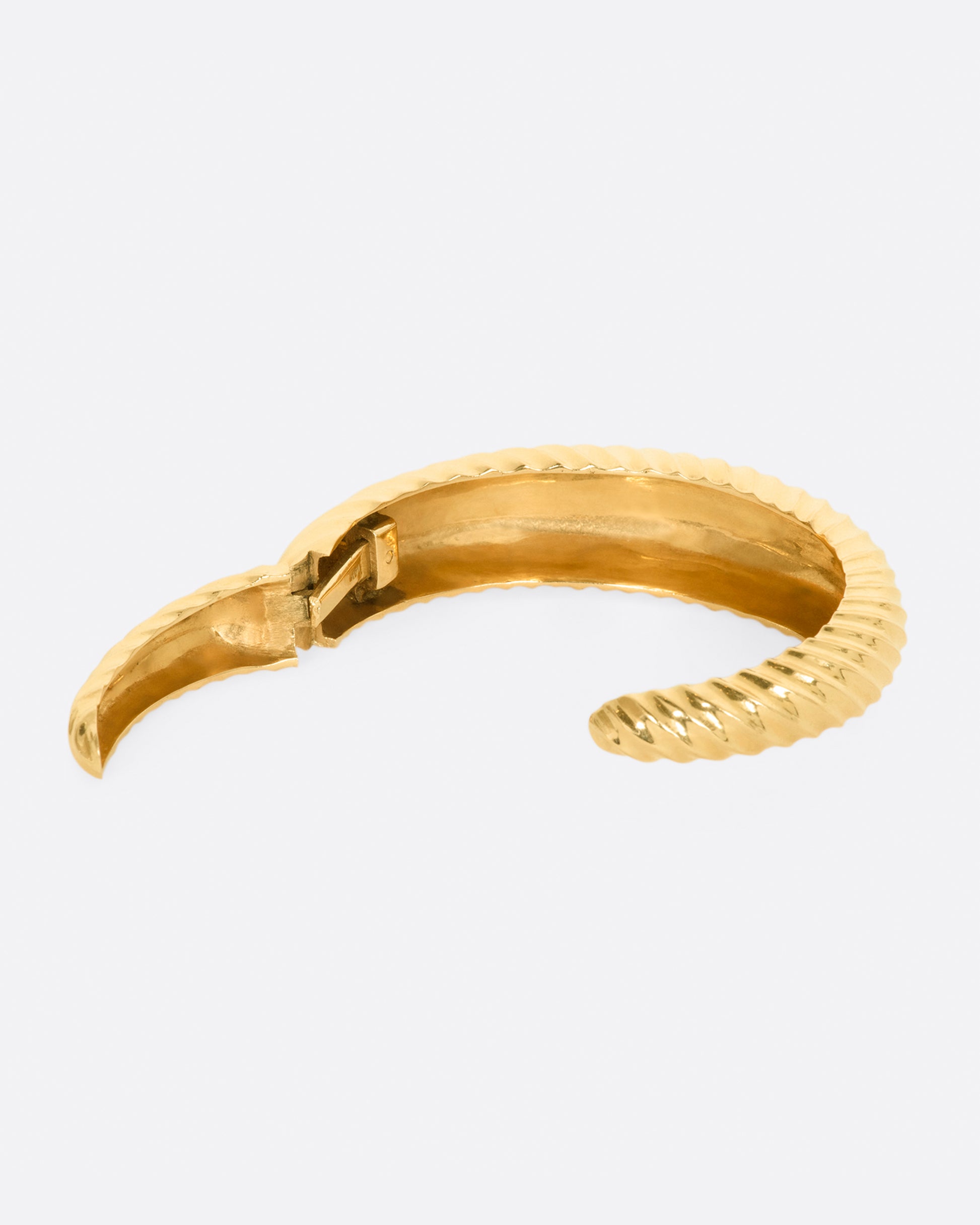 Yellow gold cuff with ridges that create a twisted look. View from the back, opened showing the hinge.