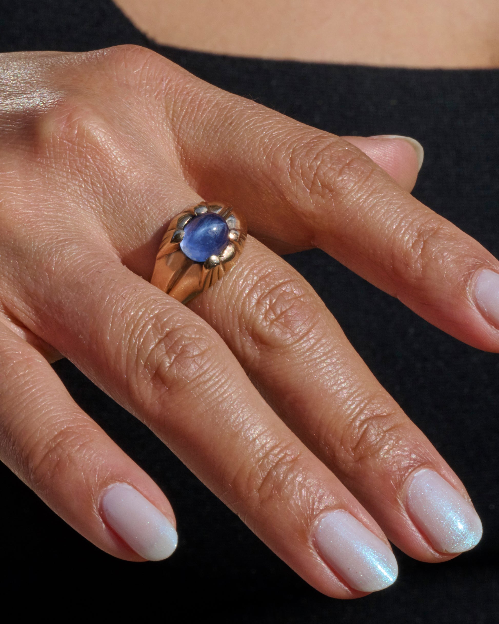 A yellow gold ring with a prong set star sapphire. View from the front.