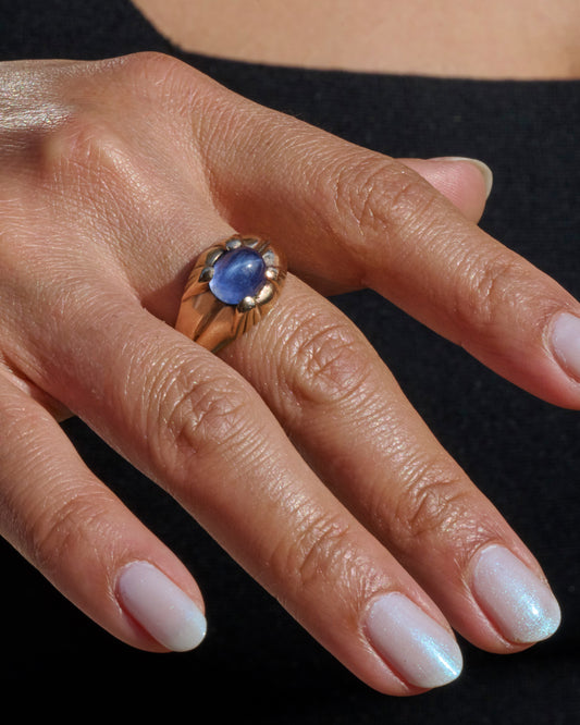 A yellow gold ring with a prong set star sapphire. View from the front.