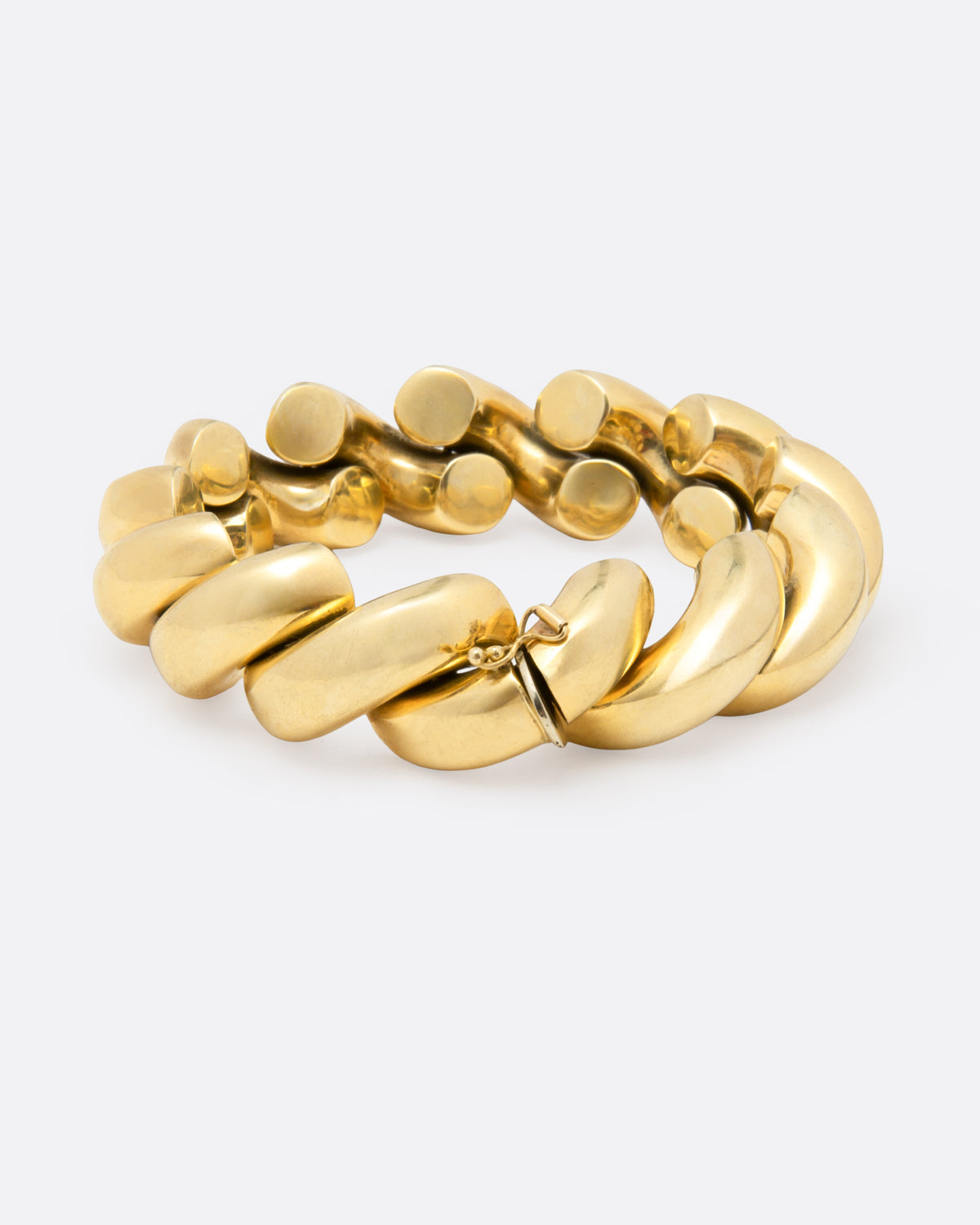 A chunky gold curved chain-link bangle bracelet with a polished finish, displayed on a clean light gray background.