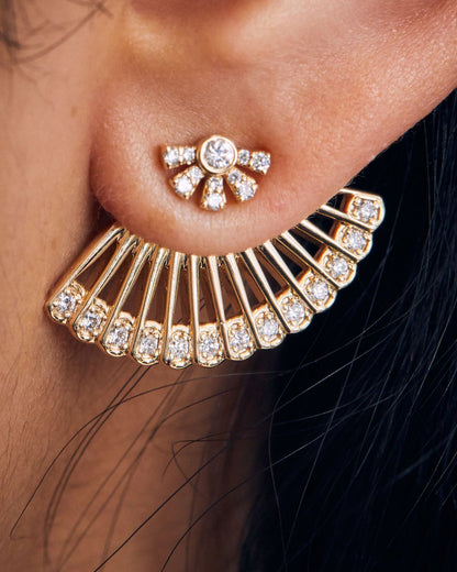 A yellow gold ear jacket shaped like a fan, with diamonds along the bottom edge. Shown from the front on a sun shaped diamond stud earring on a person's ear. 