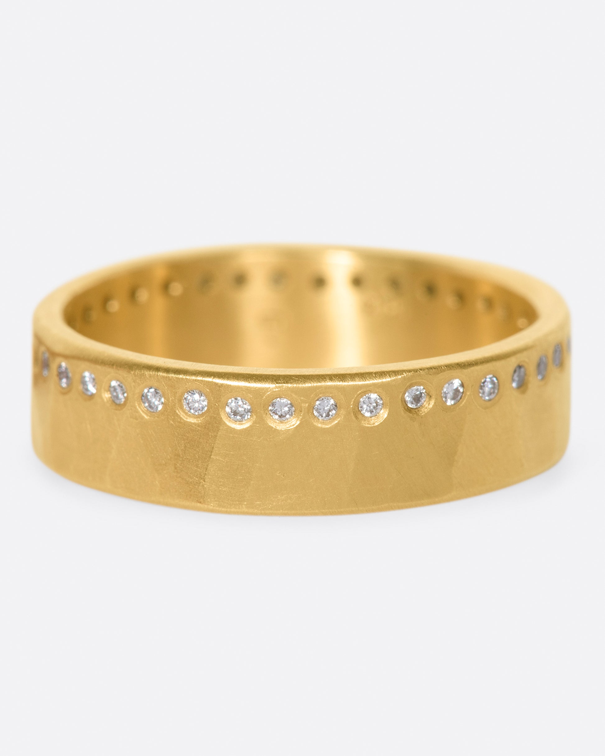 A hammered, matte gold band with a line of round diamonds all the way around.