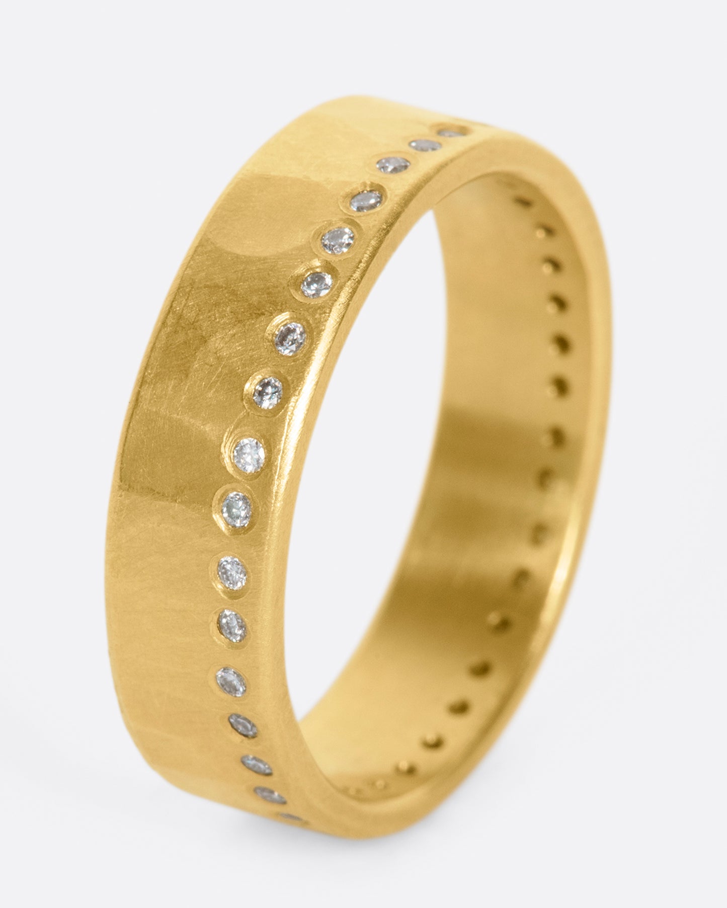 A hammered, matte gold band with a line of round diamonds all the way around.