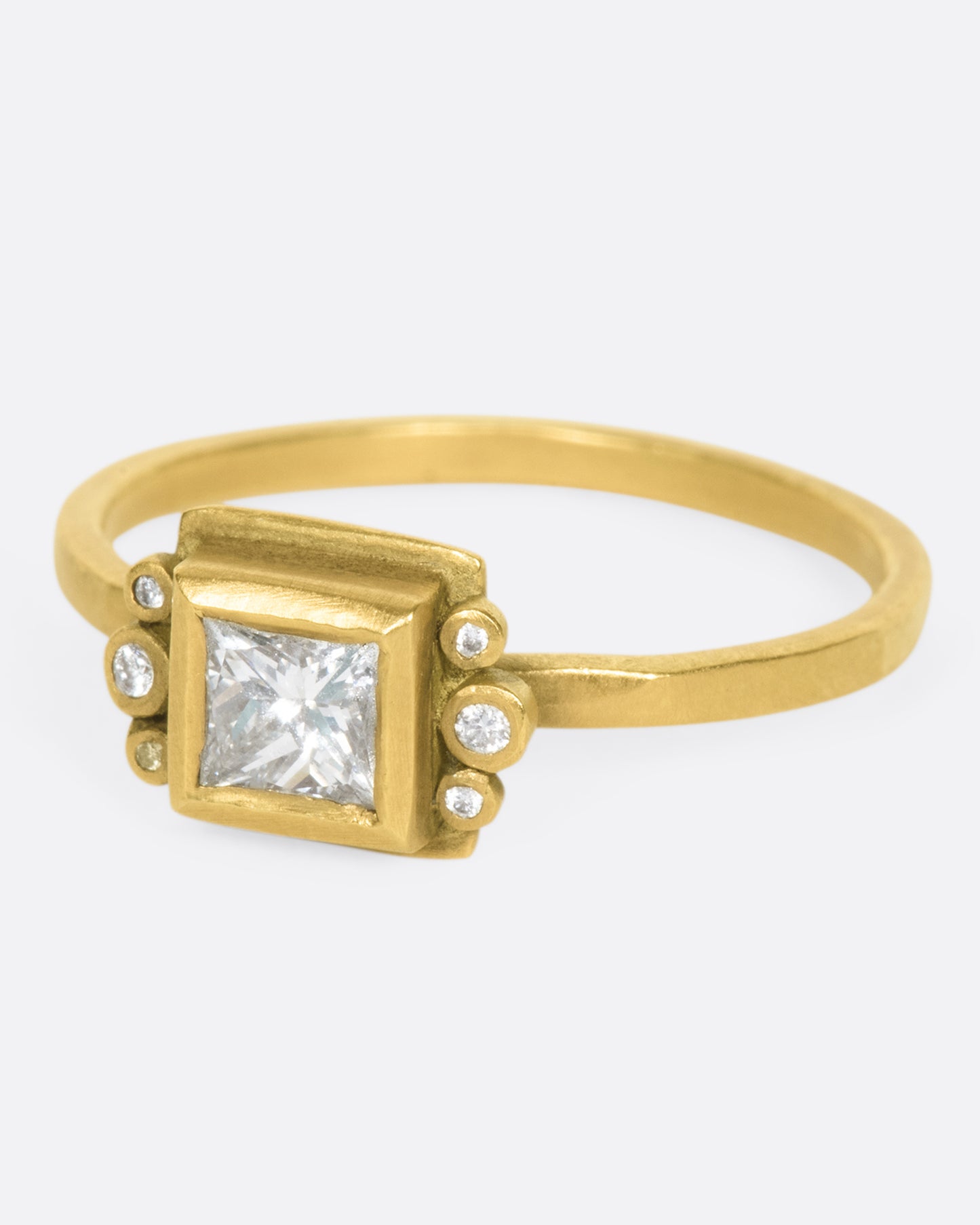 A square diamond in a matching bezel with three round diamonds on either side.