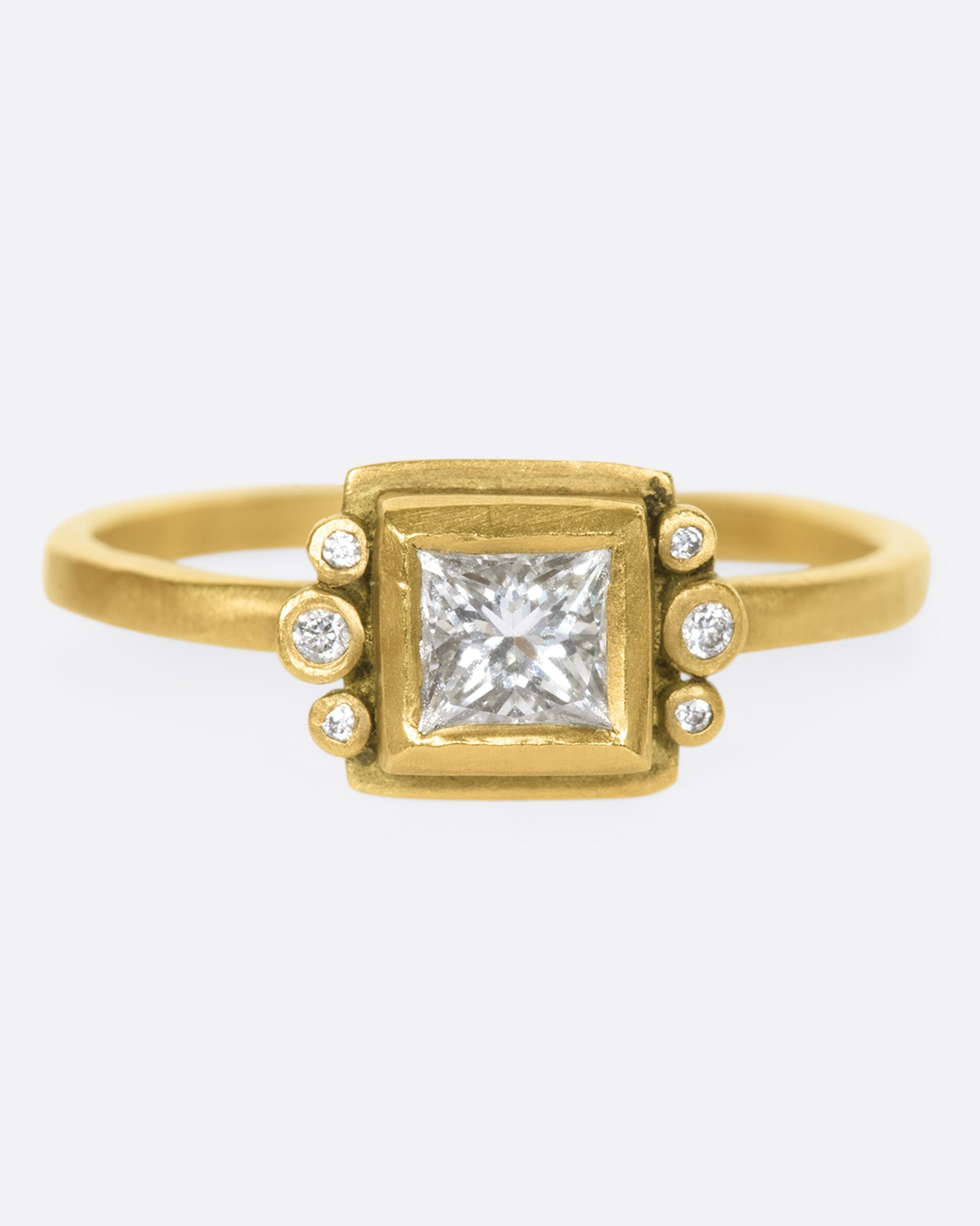 A square diamond in a matching bezel with three round diamonds on either side.