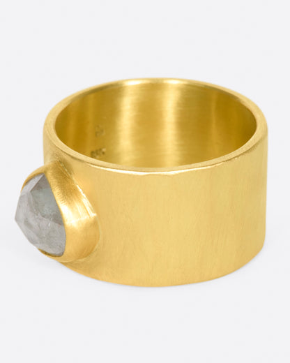 A wide, matte yellow gold hammered band with a rose cut gray diamond, shown from the side.