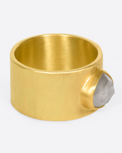 A wide, matte yellow gold hammered band with a rose cut gray diamond, shown from the side.