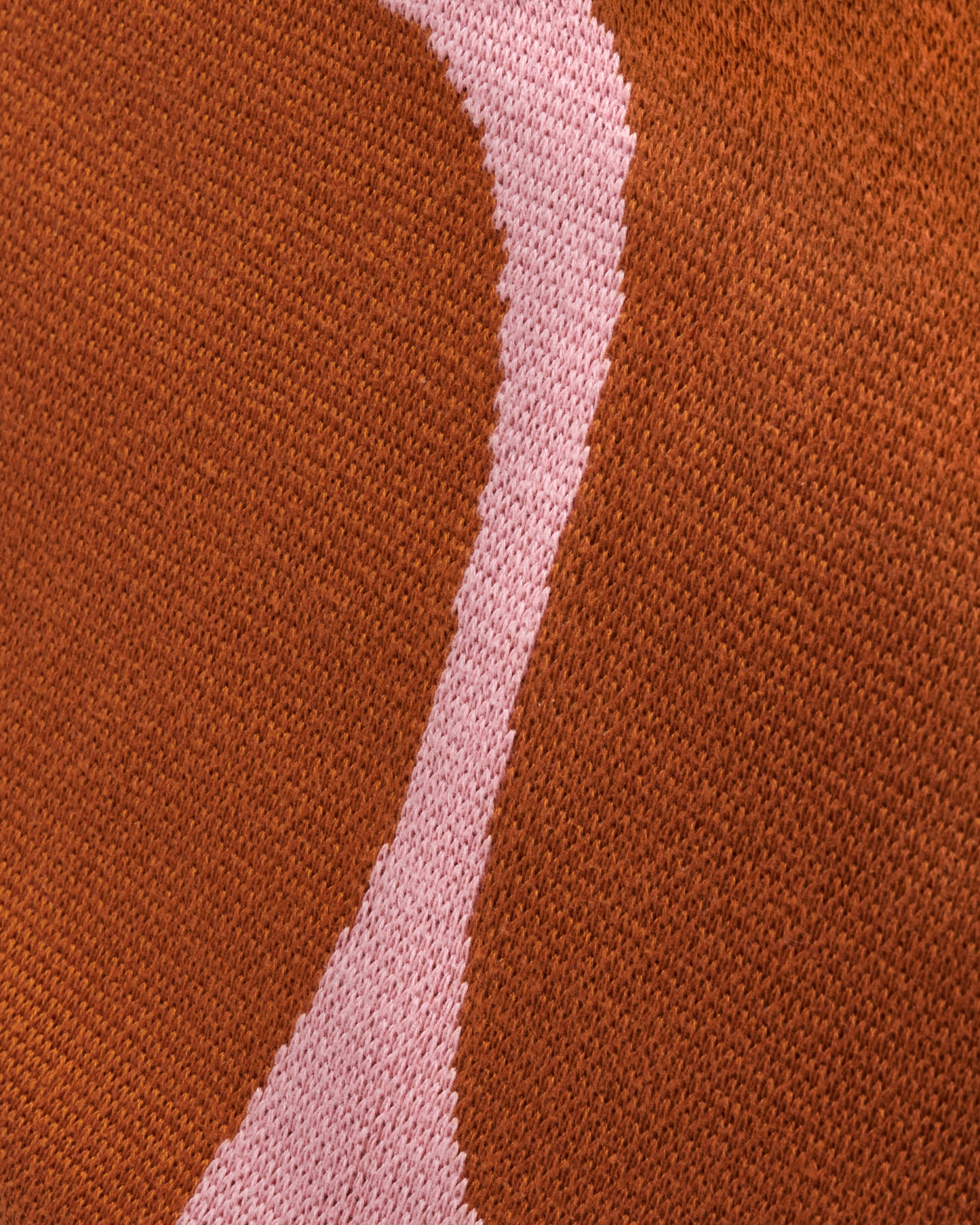 A long knit jacquard throw blanket featuring a minimalist design inspired by the Mojave desert, shown close up.