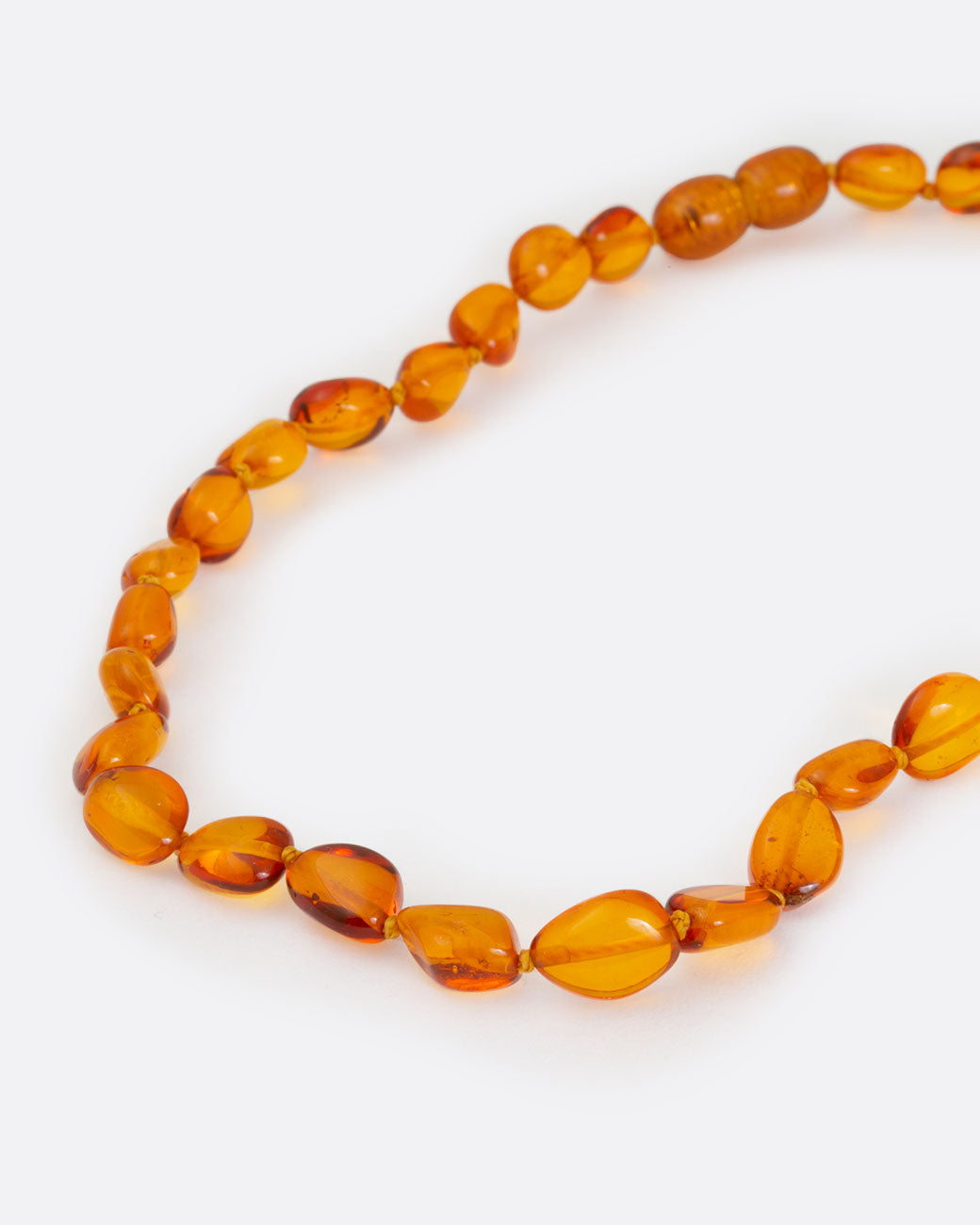 Cognac amber teething necklace, shown from the side.