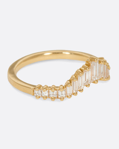 A curved crown ring lined with baguette diamonds. Shown from the side.