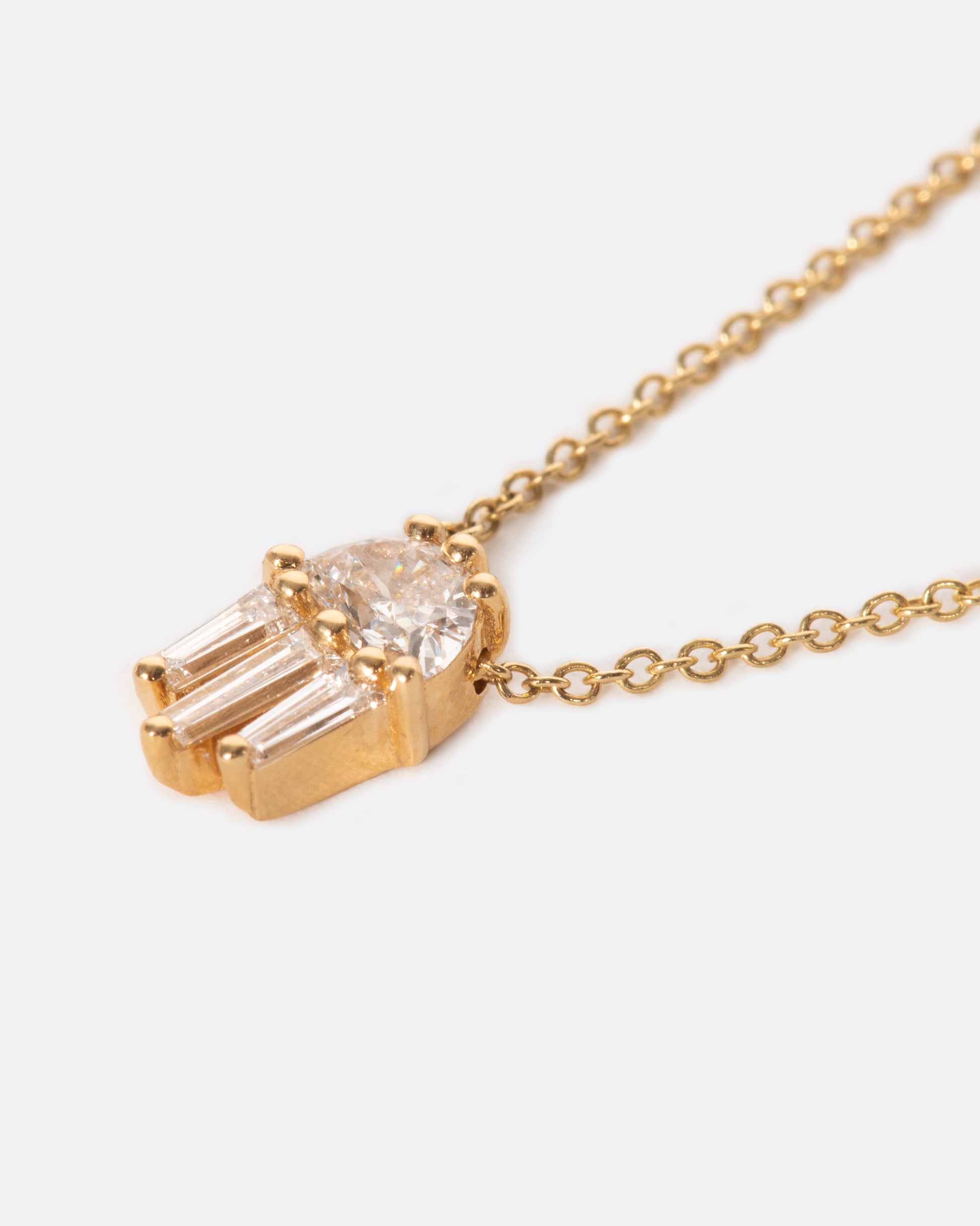 A diamond pendant necklace with a half moon and three tapered baguette diamonds.