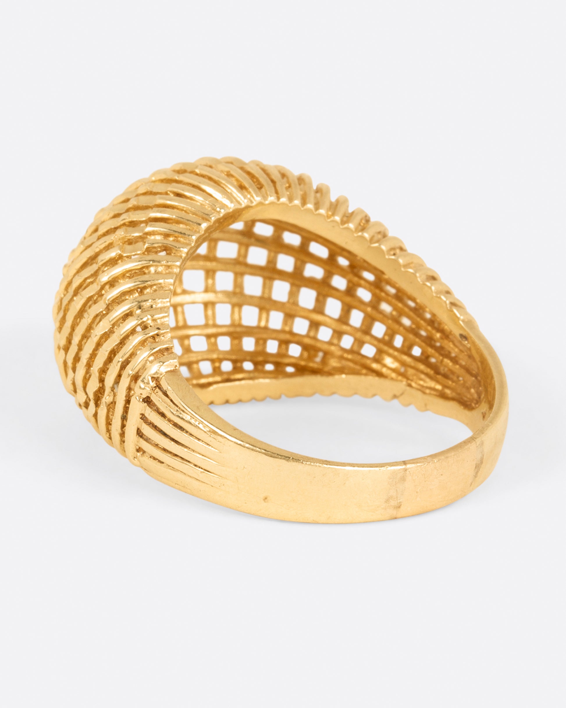 A woven yellow gold dome ring, shown from the side.