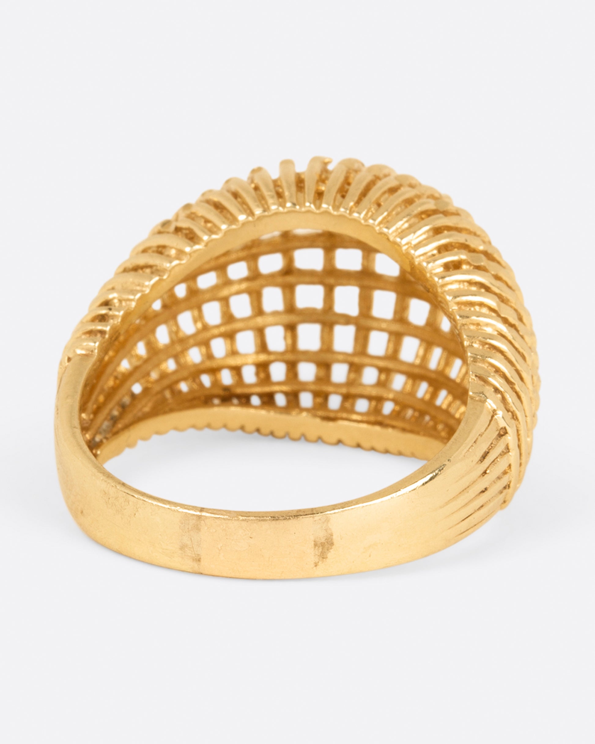 A woven yellow gold dome ring, shown from the back.