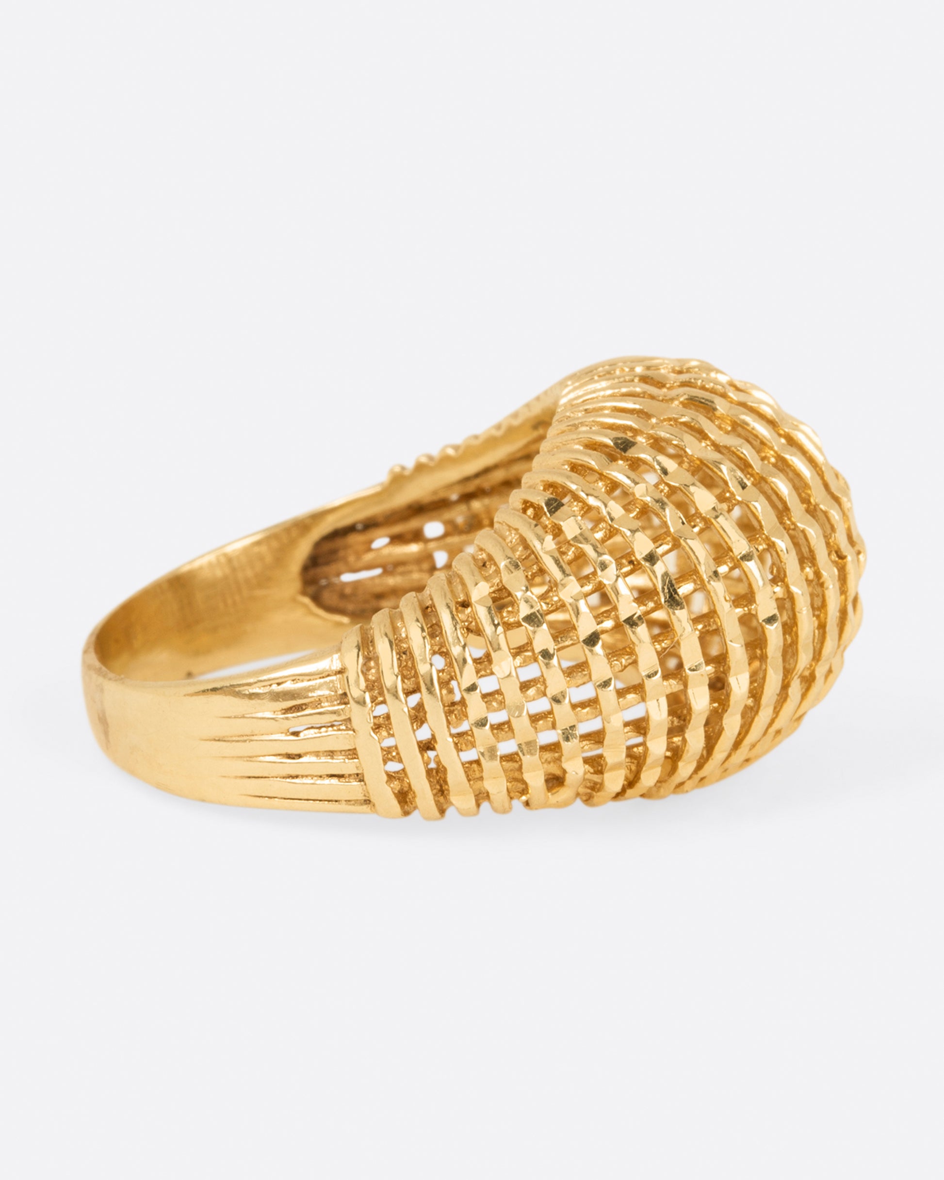 A woven yellow gold dome ring, shown from the side.