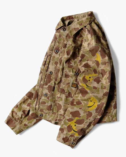 A military-like camouflage 1st jacket with smiley faces peeking out.