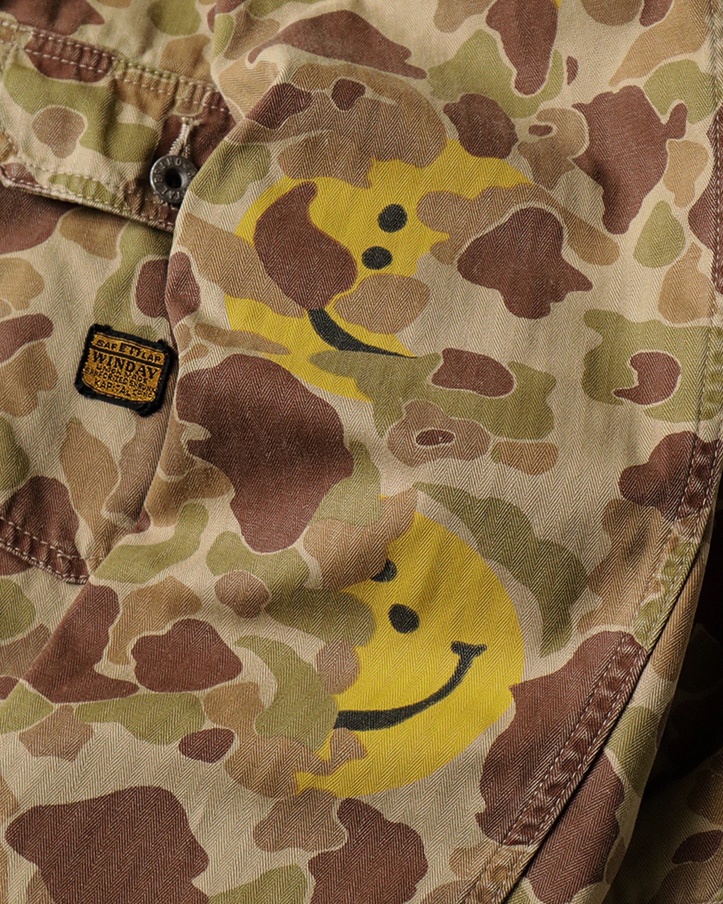 A military-like camouflage 1st jacket with smiley faces peeking out.