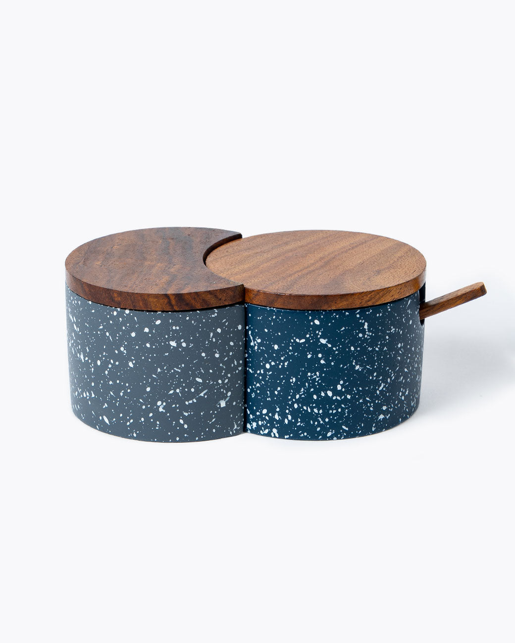 Interlocking circular salt cellar made of speckled blue and gray cement with wood lid and spoon, shown from the side.