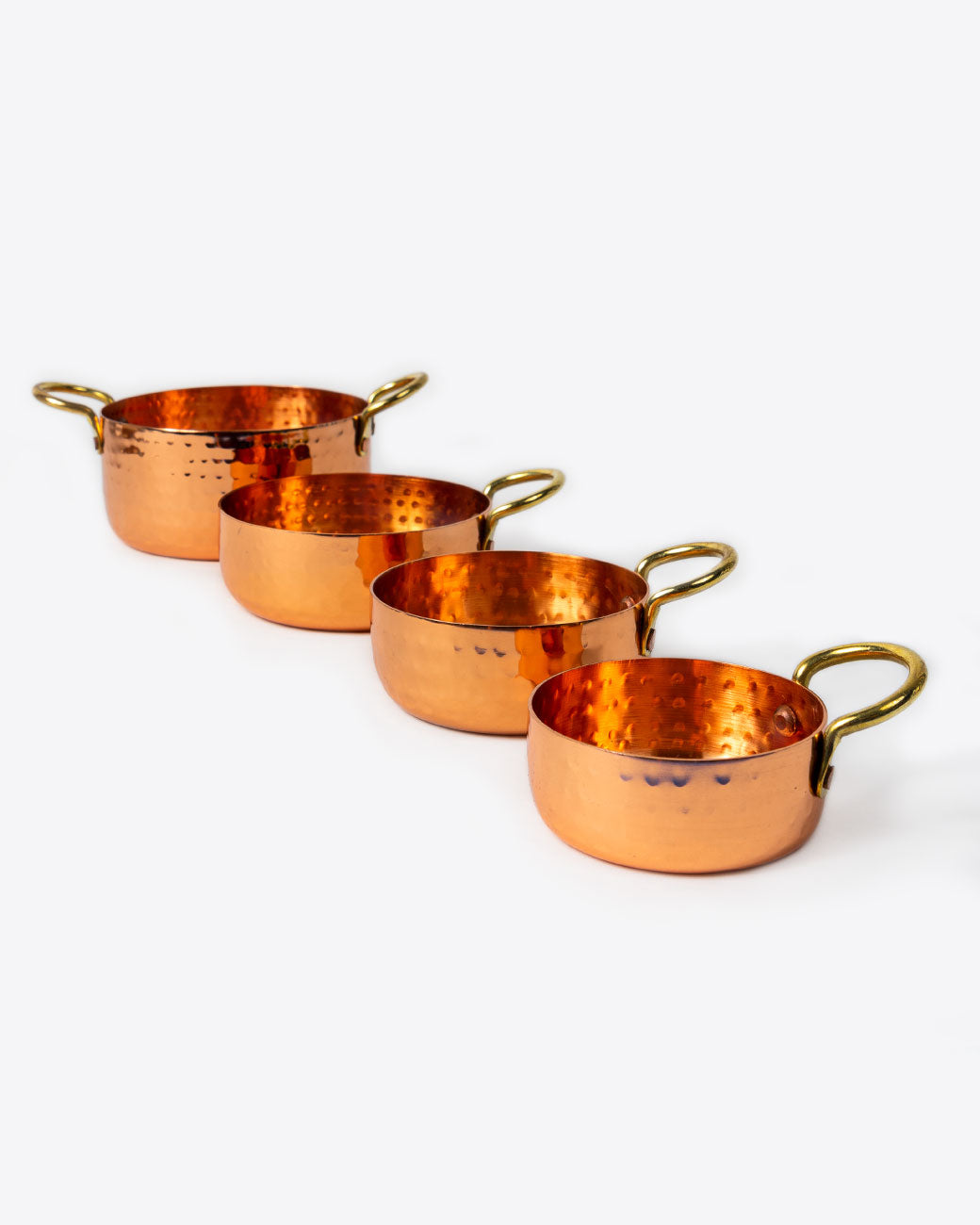 Set of four hammered copper measuring cups sitting next to one each other. 