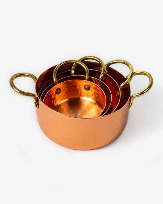 Set of four hammered copper measuring cups, stacked together.