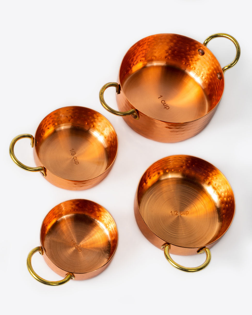 Set of four hammered copper measuring cups, shown from above.