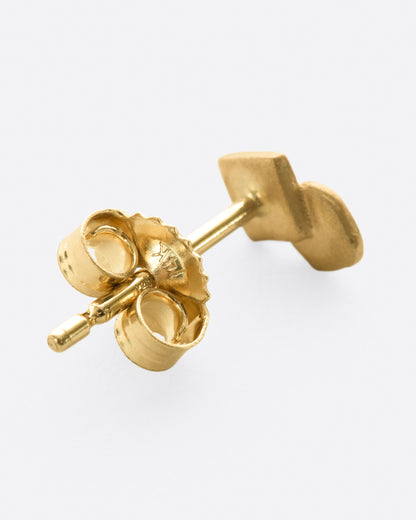 A yellow gold stud earring with overlapping circle and matte finish. Shown lying flat from the back.
