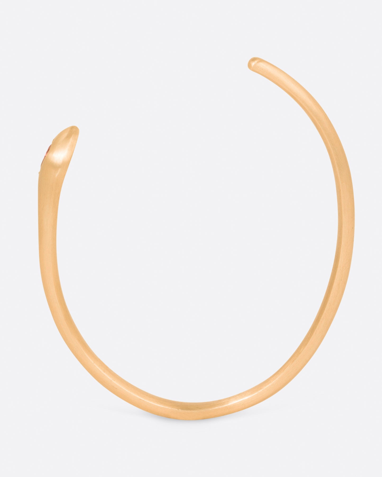 A matte yellow gold snake cuff bracelet with a pear shaped pink sapphire on its head, shown standing up, from the side.