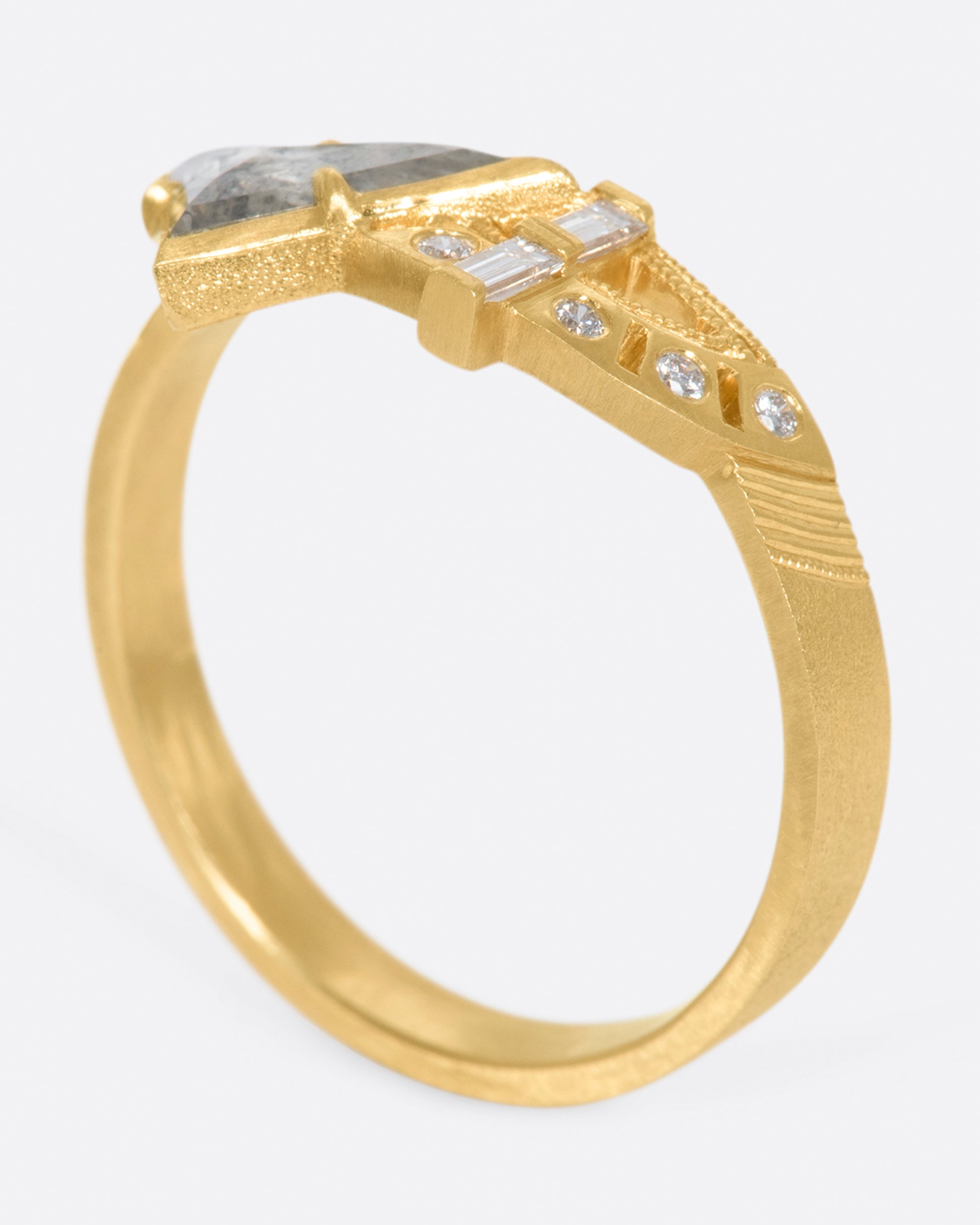 A wide flat band with a salt & pepper trillion cut diamond, gold arches, and round diamonds at its center.