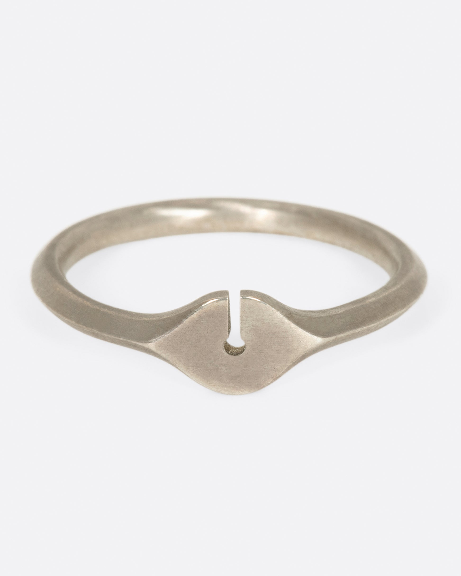 A brush sterling silver ring with a knife-edge band and an elliptical face with a keyhole cutout.