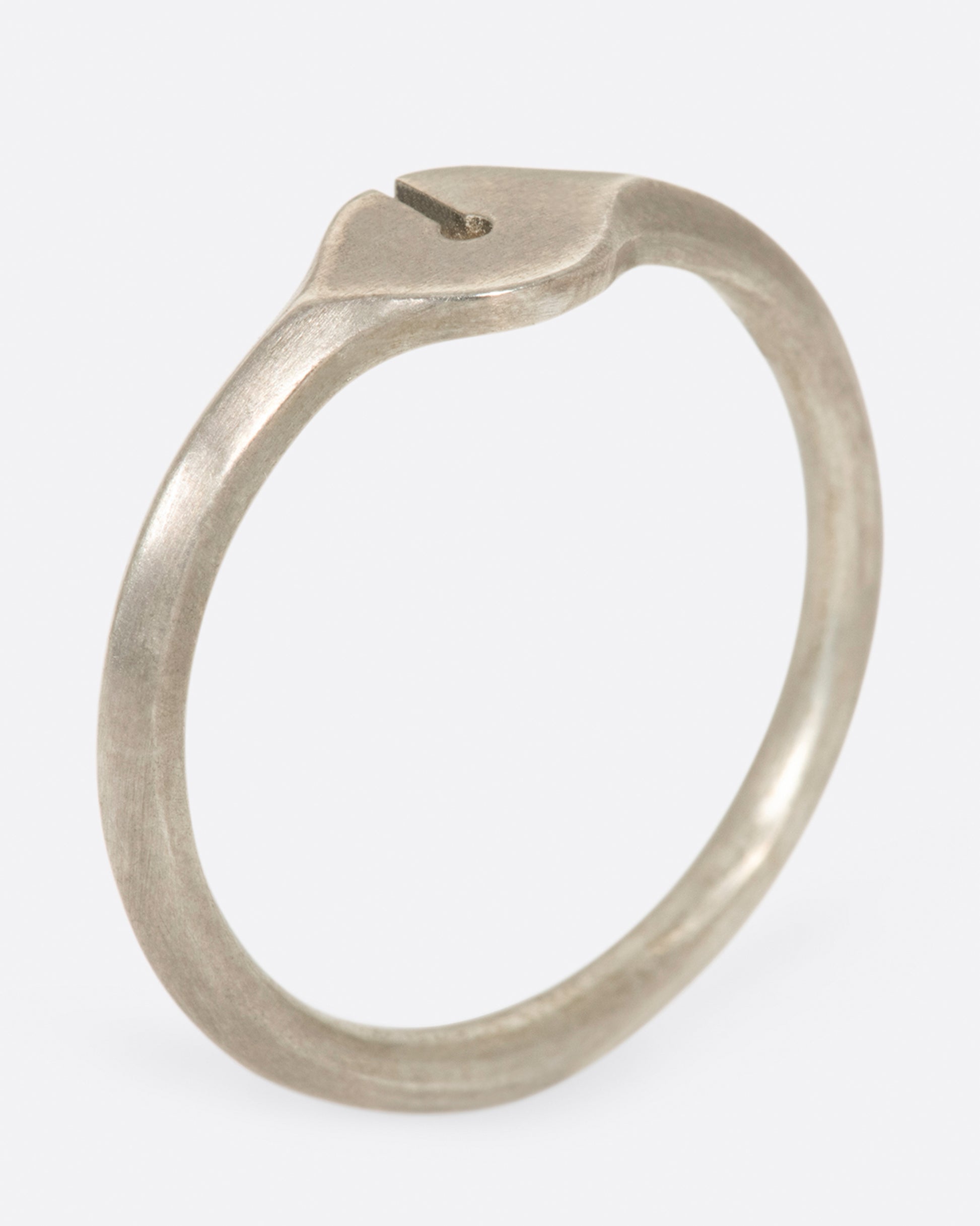 A brush sterling silver ring with a knife-edge band and an elliptical face with a keyhole cutout.