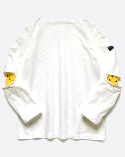 A white long sleeve shirt with hidden yellow smileys peeking out at the elbows. Shown from the front.
