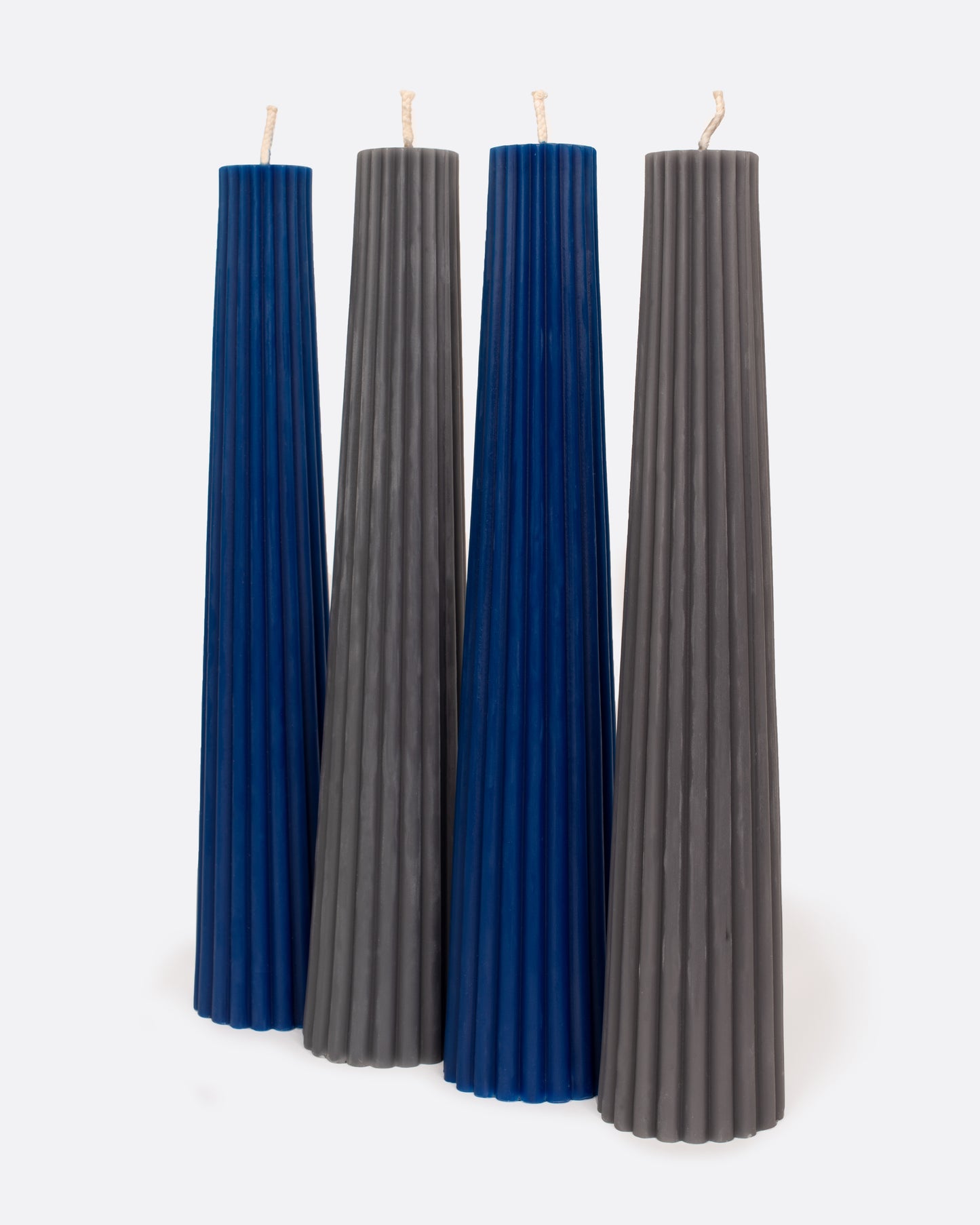 Four beeswax candles, two blue and two gray, standing in alternating colors.