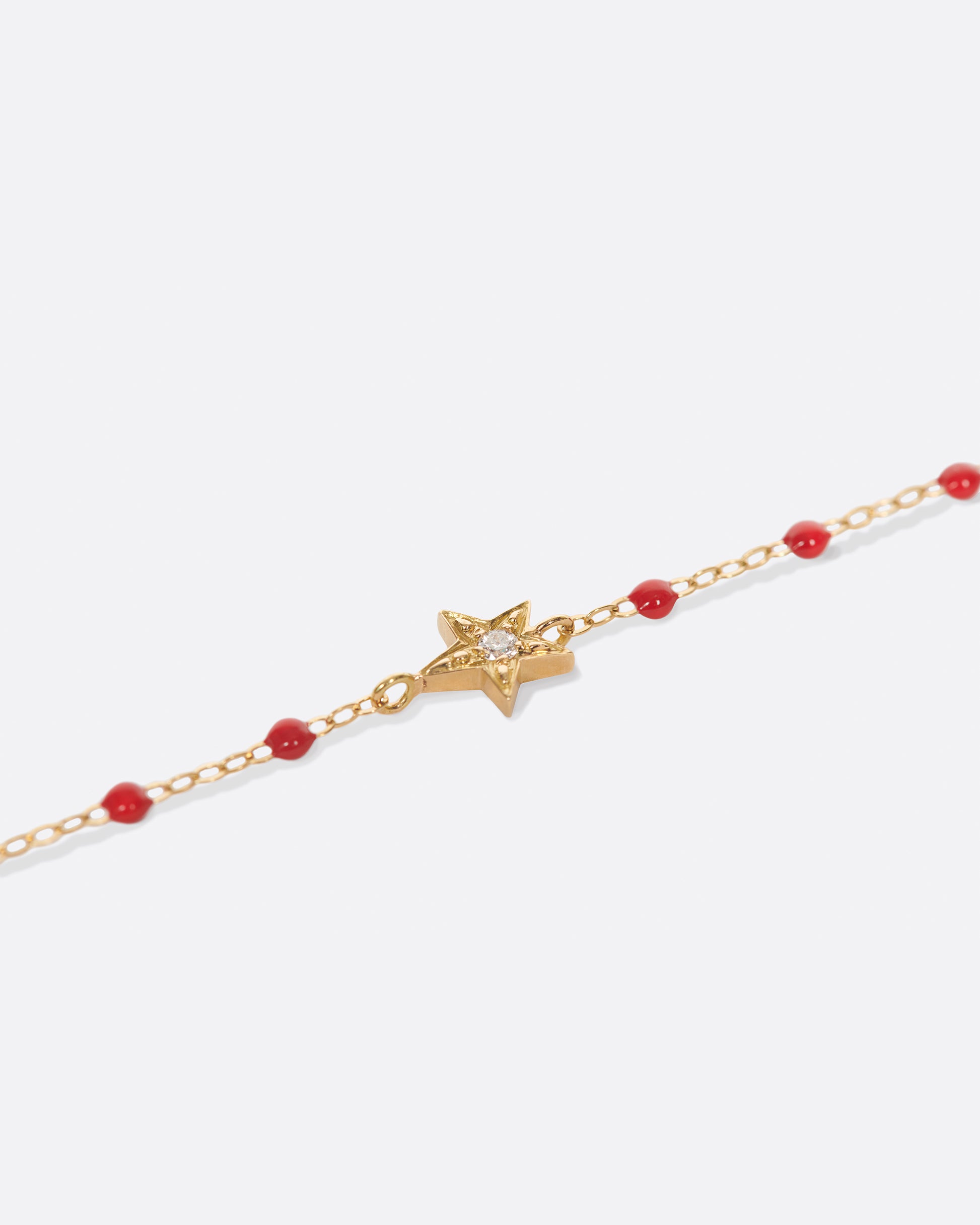 A classic Gigi Clozeau bracelet with poppy red resin and a five point star at its center.