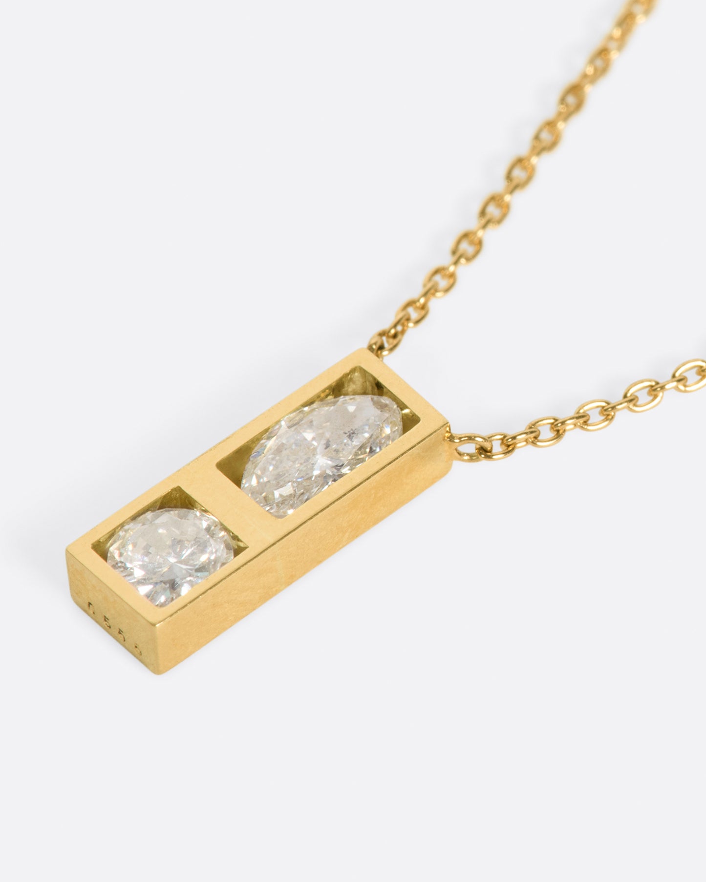 A geometric pendant necklace with two diamonds, shown laying flat.