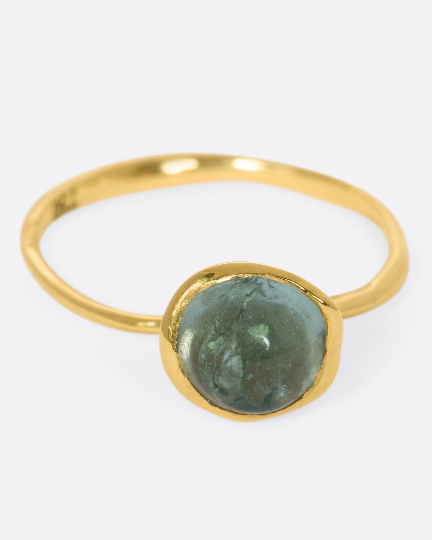 A wonky gold ring with a blue tourmaline cabochon set atop it.
