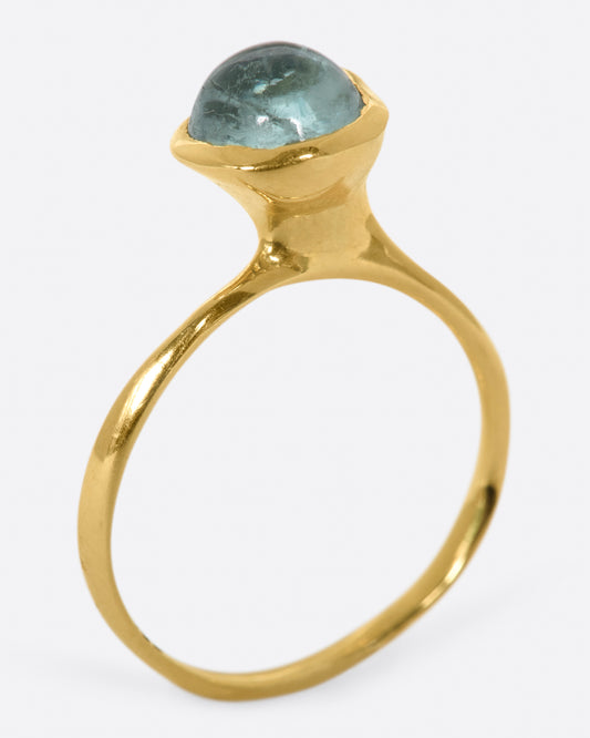A wonky gold ring with a blue tourmaline cabochon set atop it.