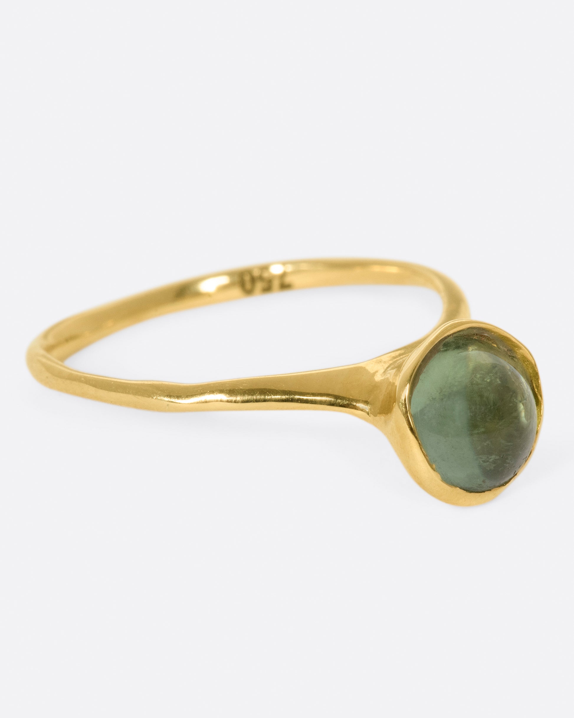 A sage-y green tourmaline cabochon is set in a bezel setting atop this ring.