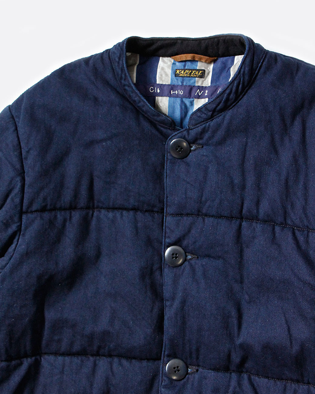 Close up of the collar of Kapital quilted denim jacket with button closure.