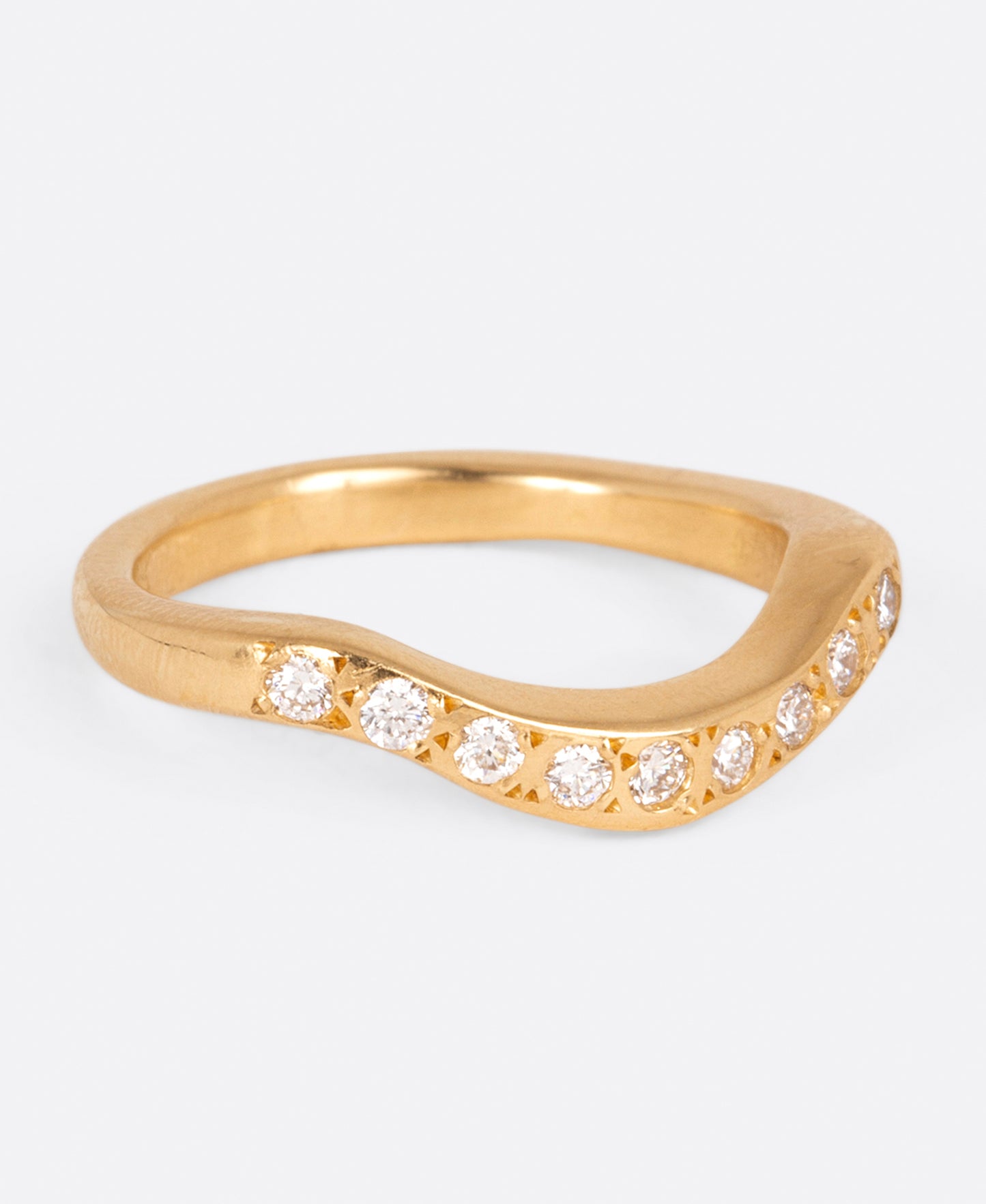 A curved yellow gold band with nine round white diamonds, shown from the side.