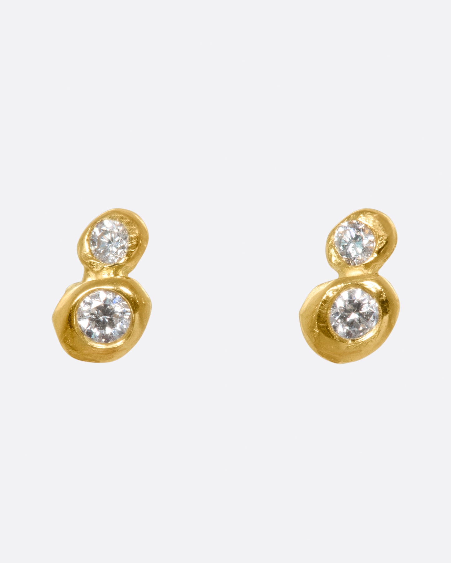 A pair of earrings with two diamonds embedded in gold on each.