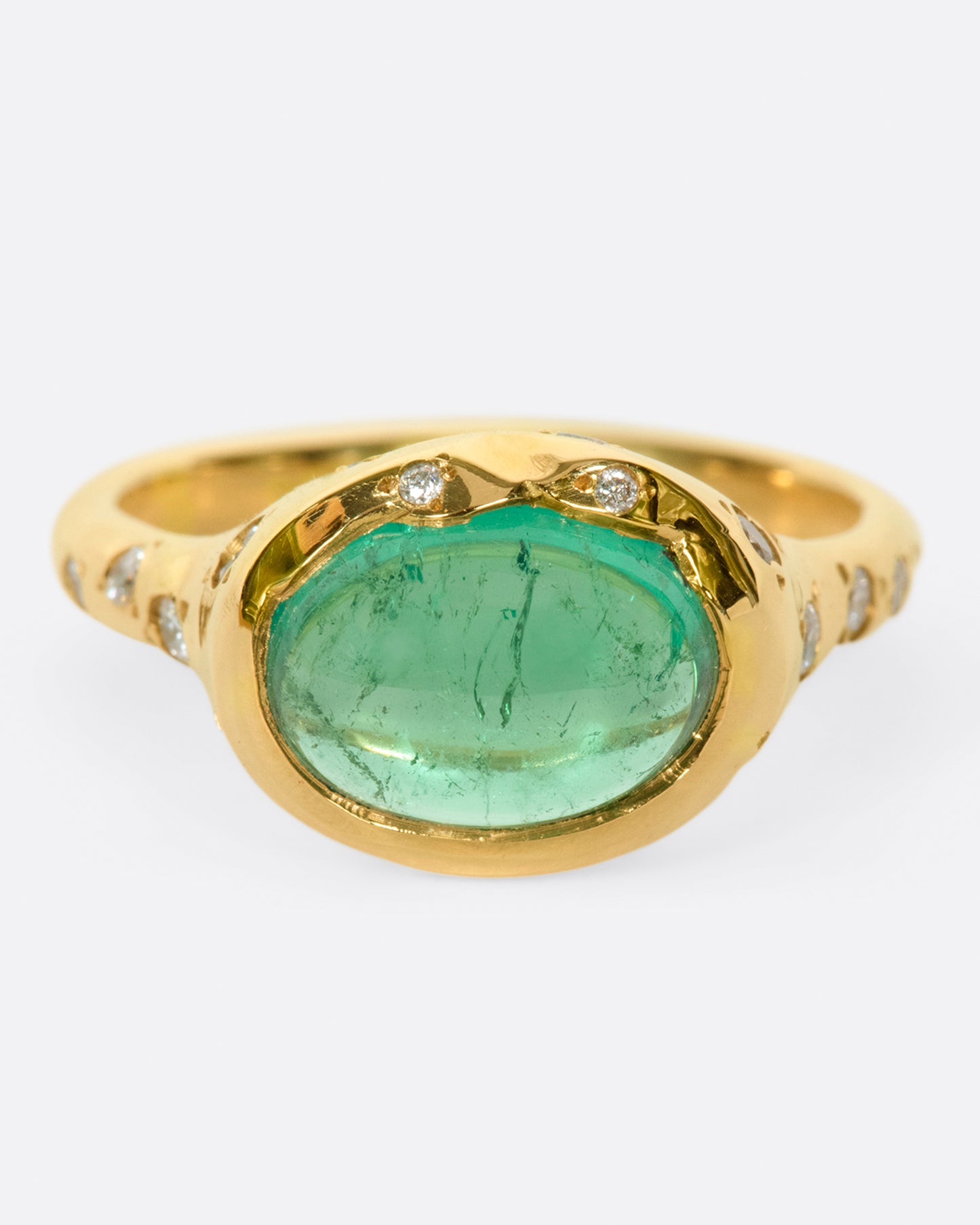 A bright green emerald cabochon sits at the center of this signet style ring.