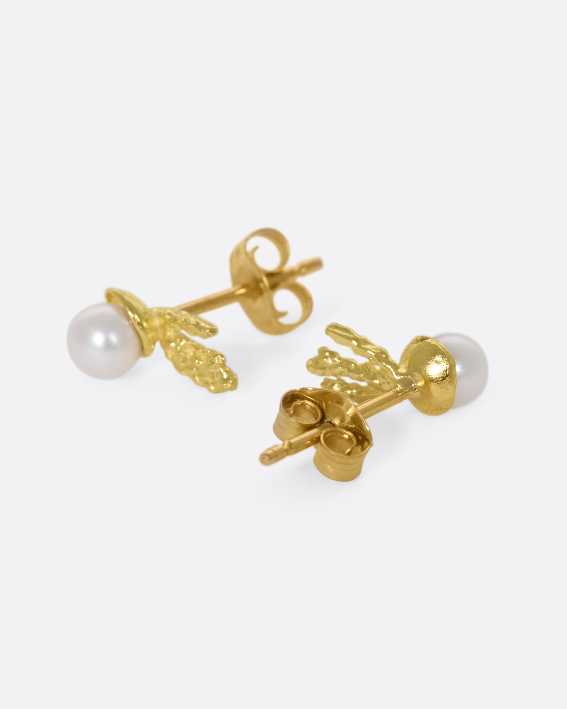 A pair of comet-like studs with Akoya pearls and gold trails.