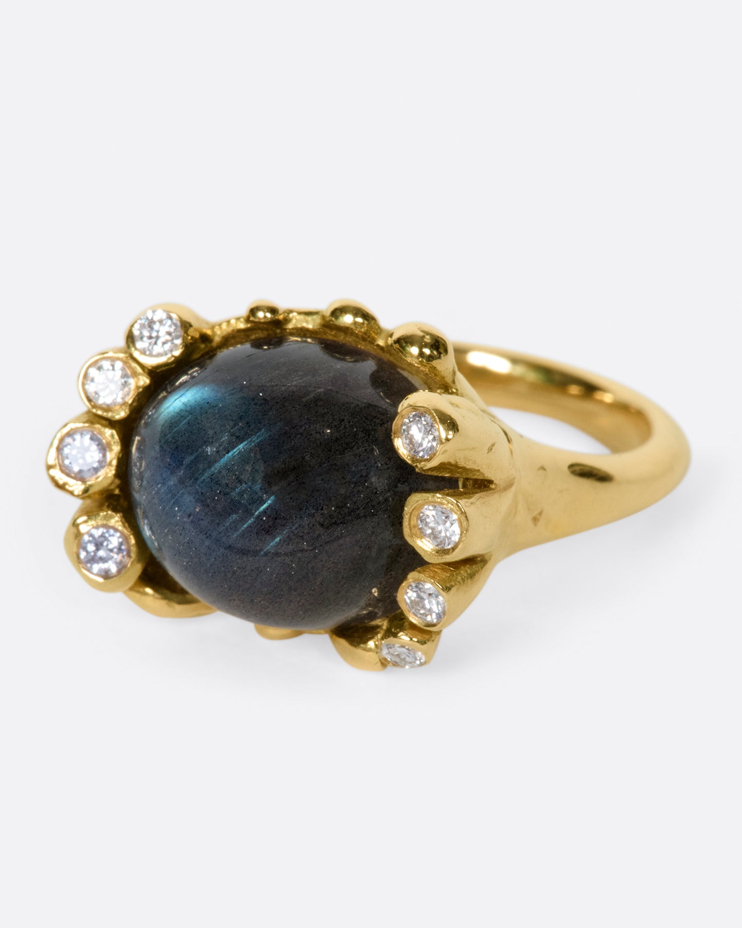 An iridescent labradorite cabochon is nestled amongst diamonds in its handcrafted setting.