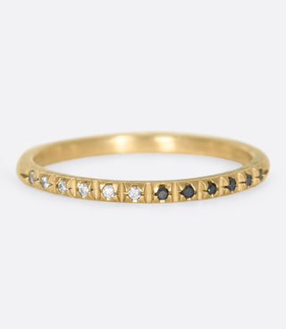 A simple gold band half lined with black and white diamonds.