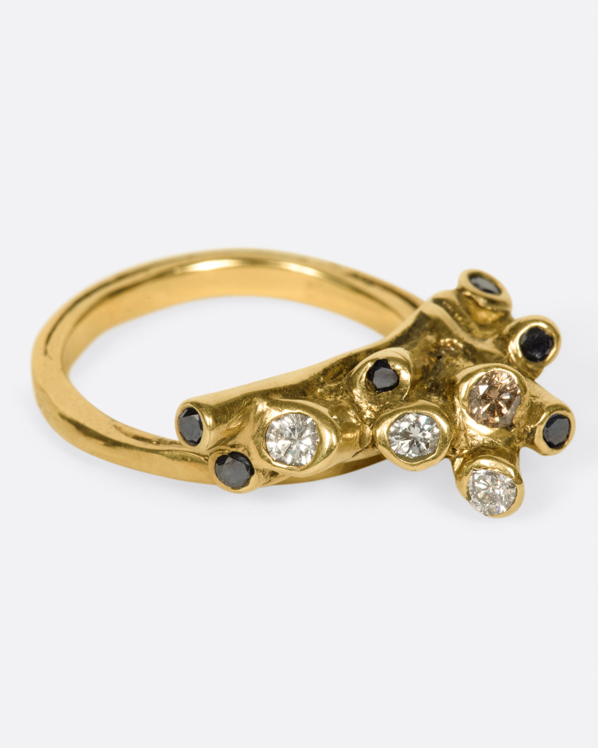 A ring with white, black, and cognac diamonds set in an anemone-like cluster.